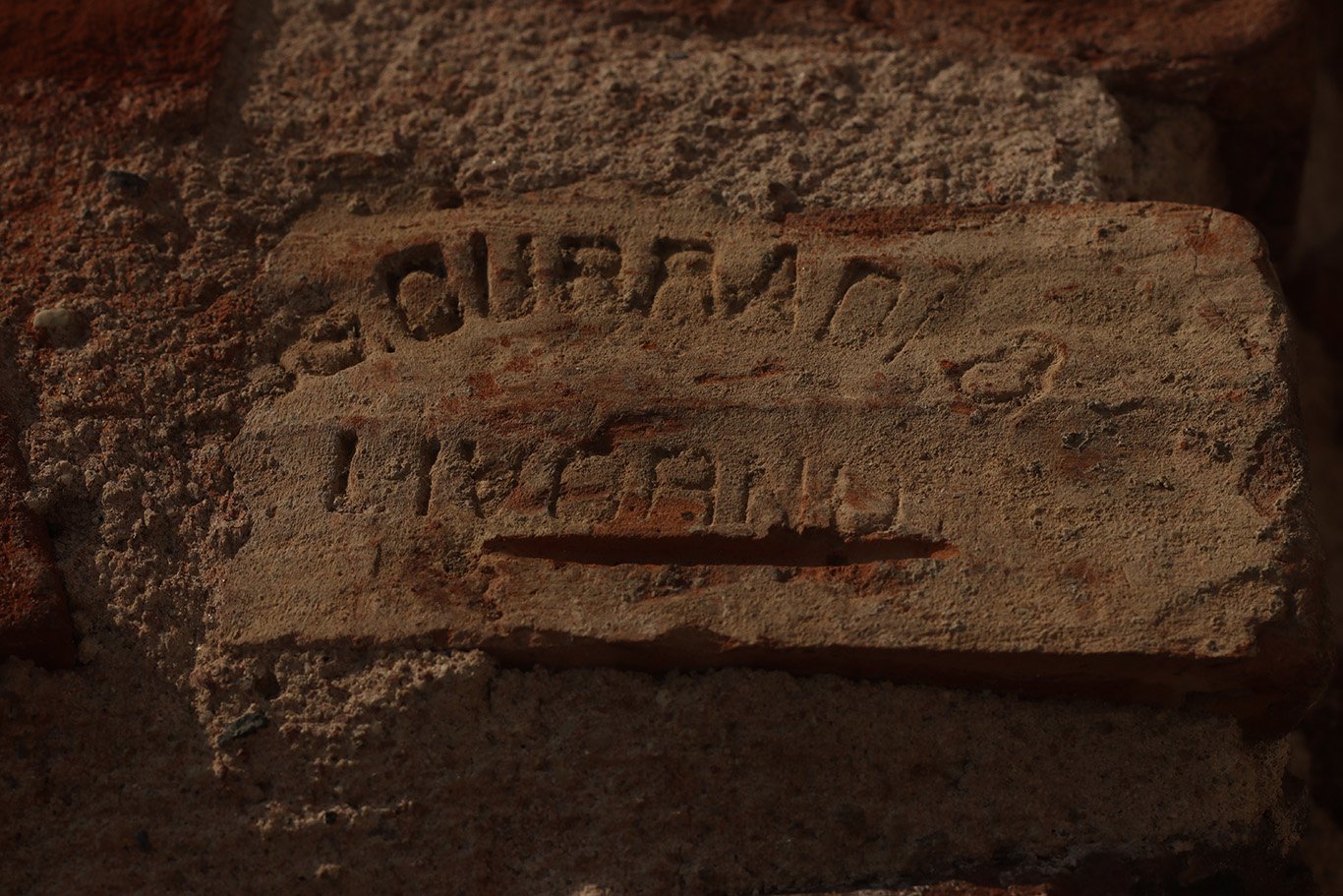 An unreadable writing carved in a beige stone wall.